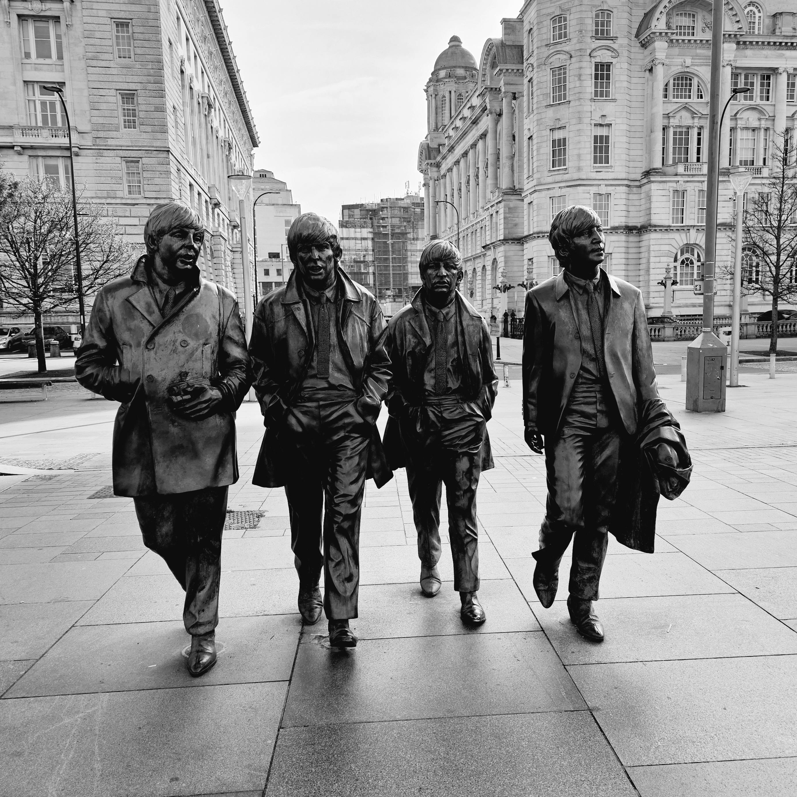 A metal statue of men walking in a road